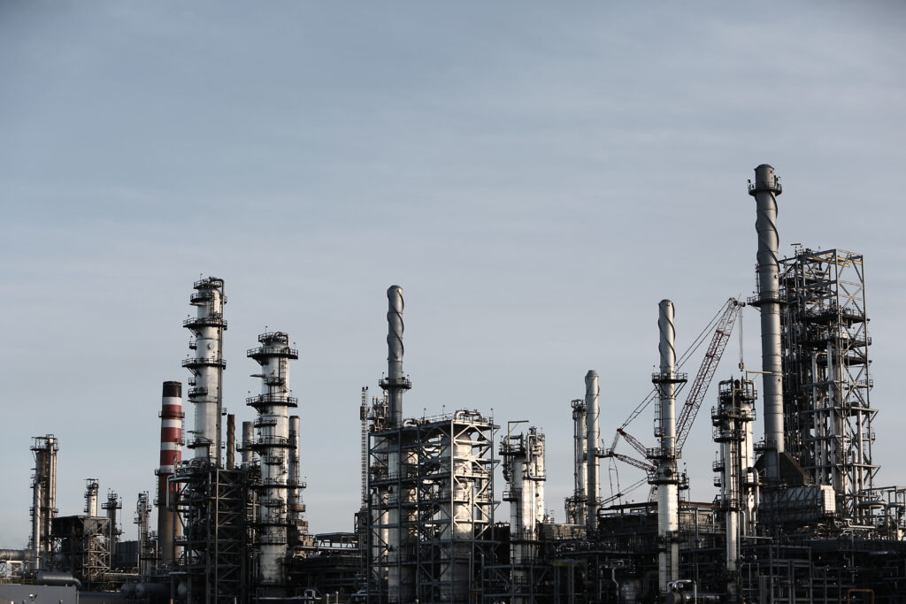 service-1 Skyline view of an industrial factory with tall chimneys against a clear sky.