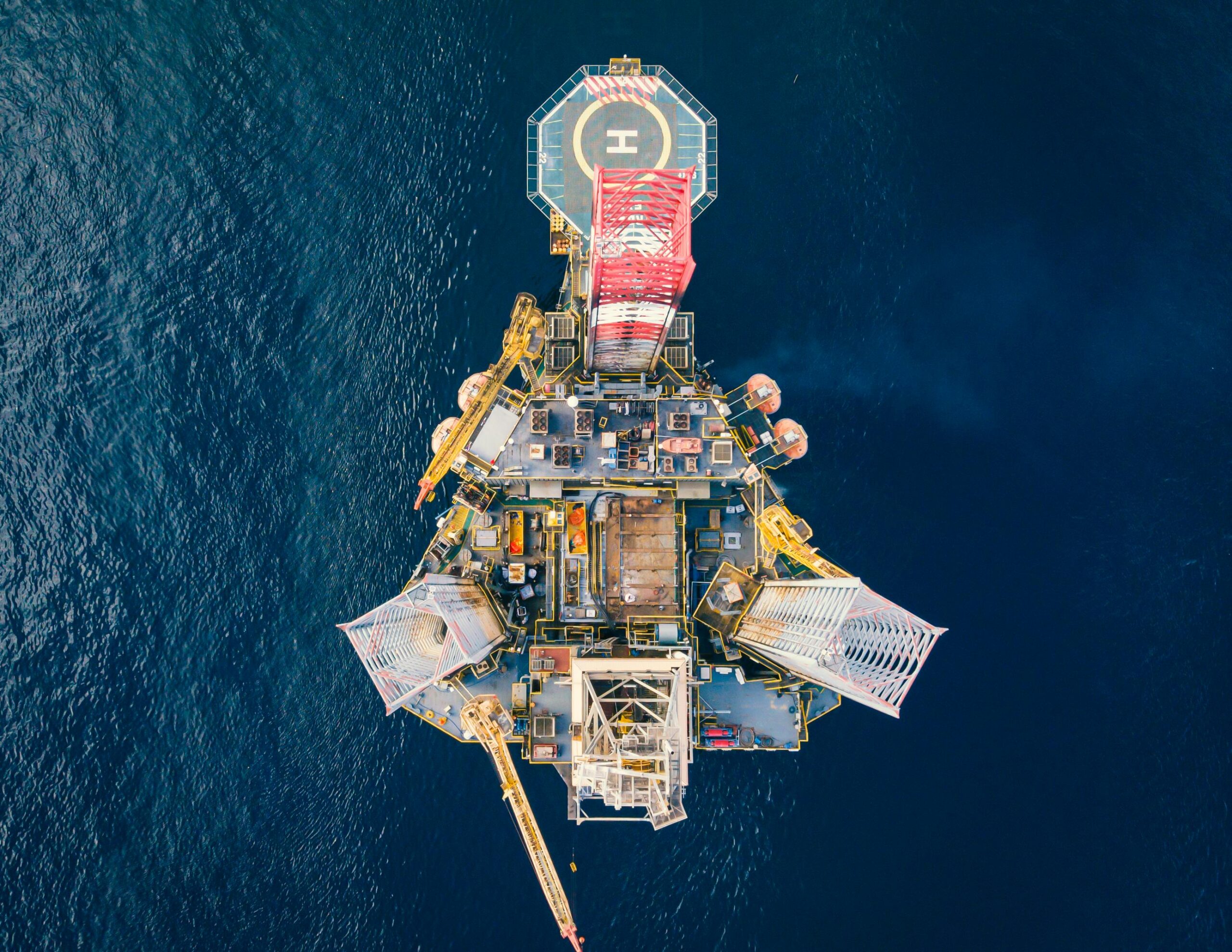 service-1 High-angle view of an offshore oil platform with helipad surrounded by deep blue ocean.
