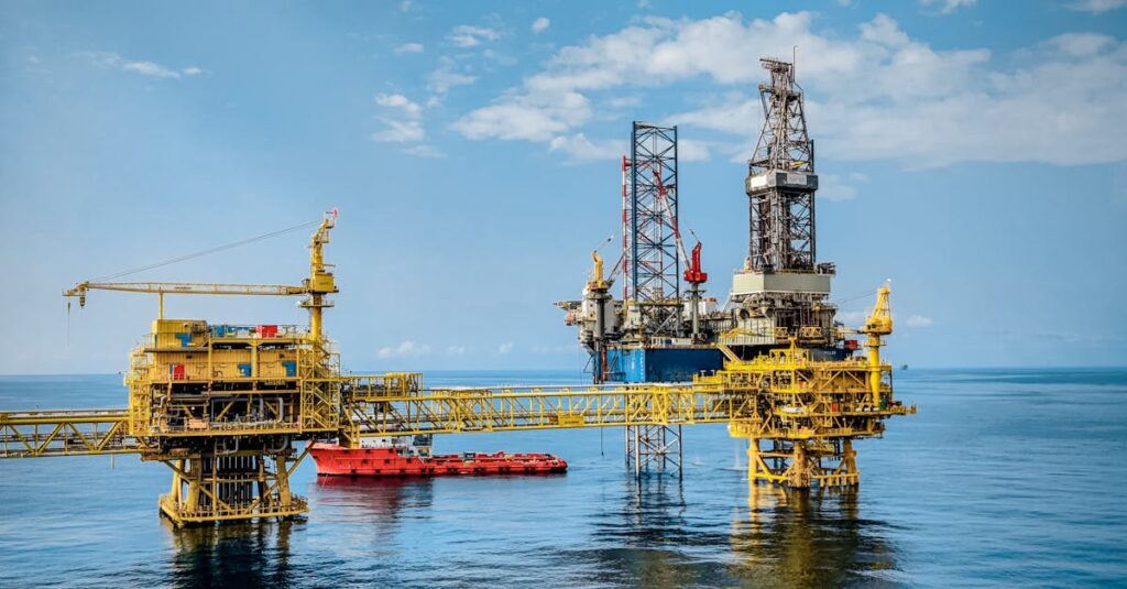 About A vibrant offshore oil rig under a clear sky, reflecting in the calm blue sea.